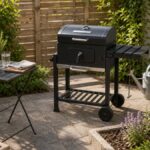 Sicherer Grillplatz auf einer Steinfläche mit Abstand zu Pflanzen und Zaun